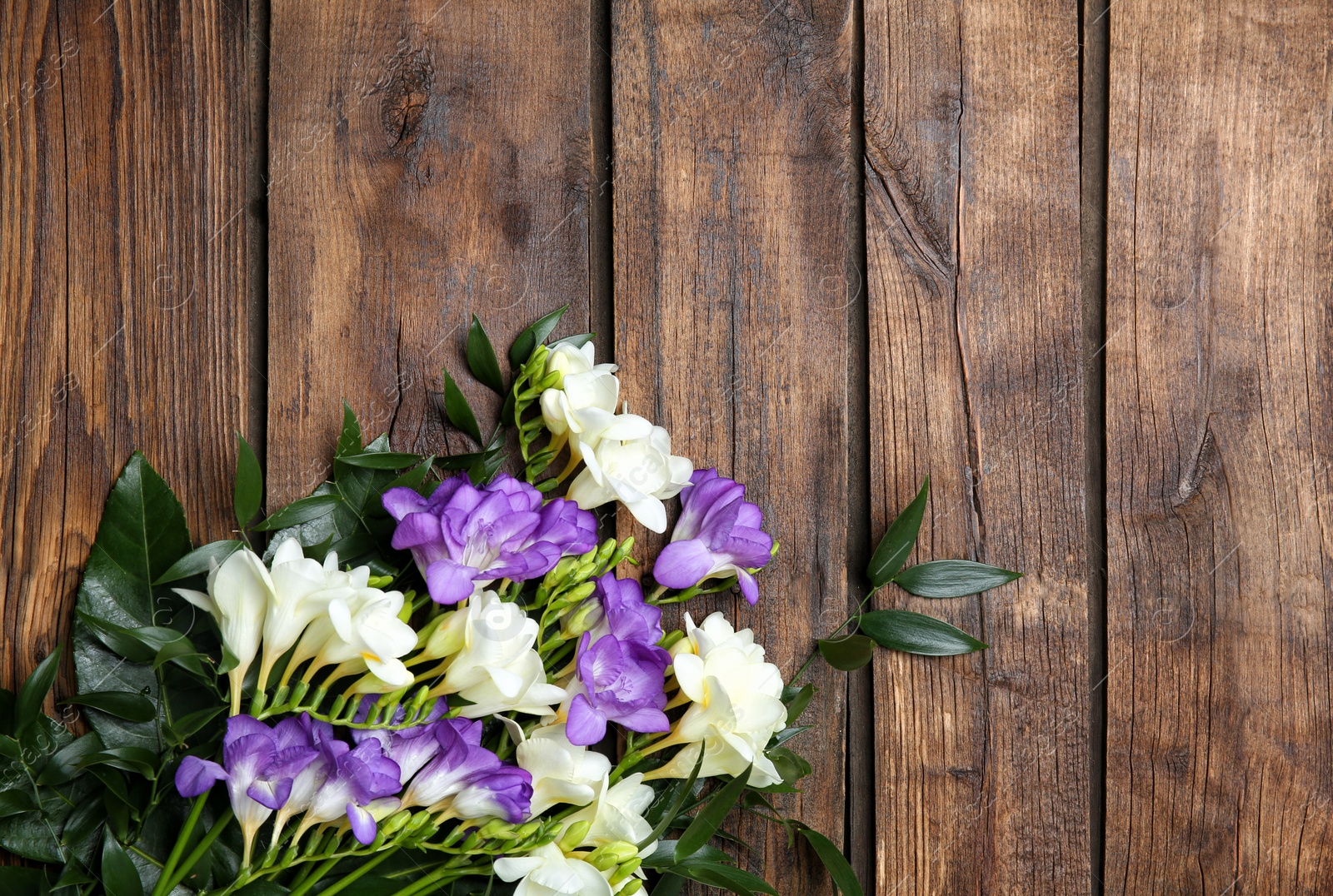 Photo of Beautiful freesia bouquet on wooden background