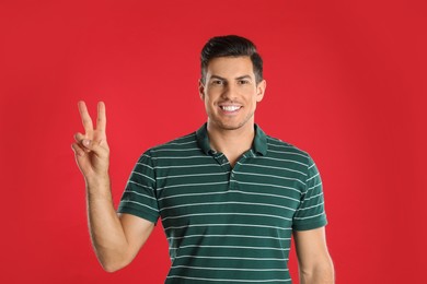 Photo of Man showing number two with his hand on red background