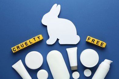 Photo of Cubes with text Cruelty Free, personal care products and figure of rabbit on blue background, flat lay. Stop animal tests