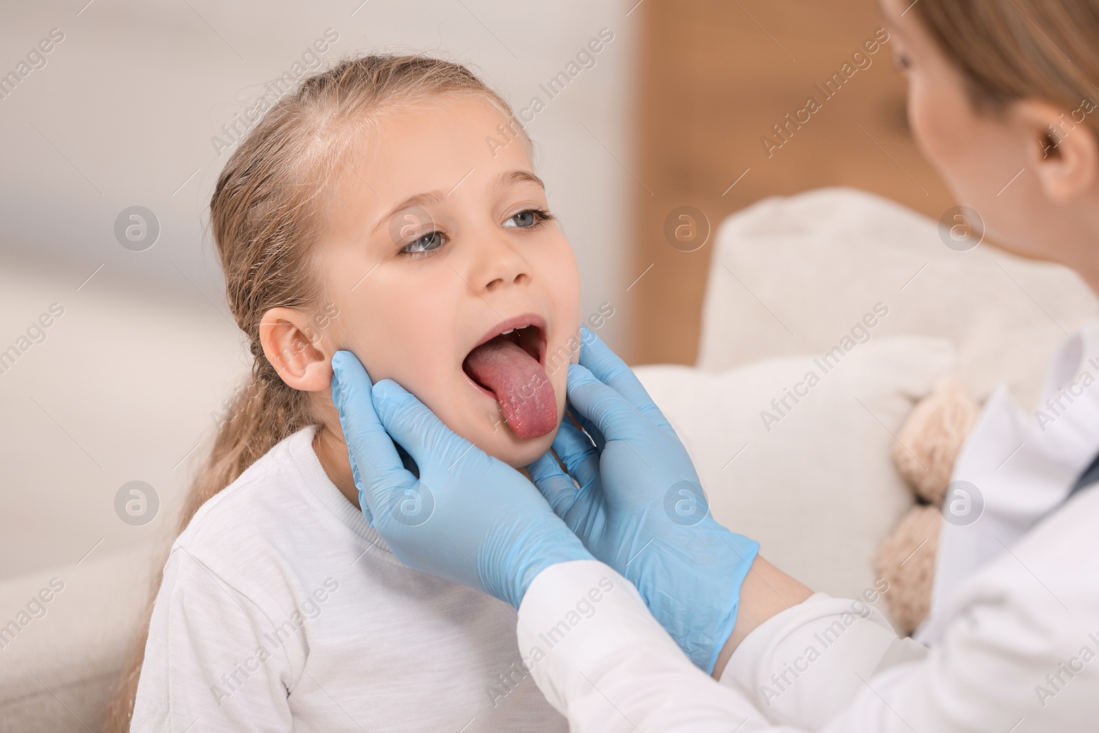 Photo of Doctor in gloves examining girl`s oral cavity indoors