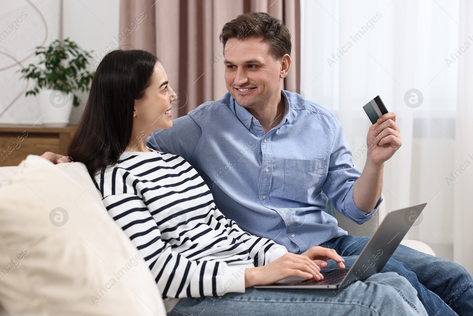 Photo of Happy couple with laptop and credit card shopping online together at home