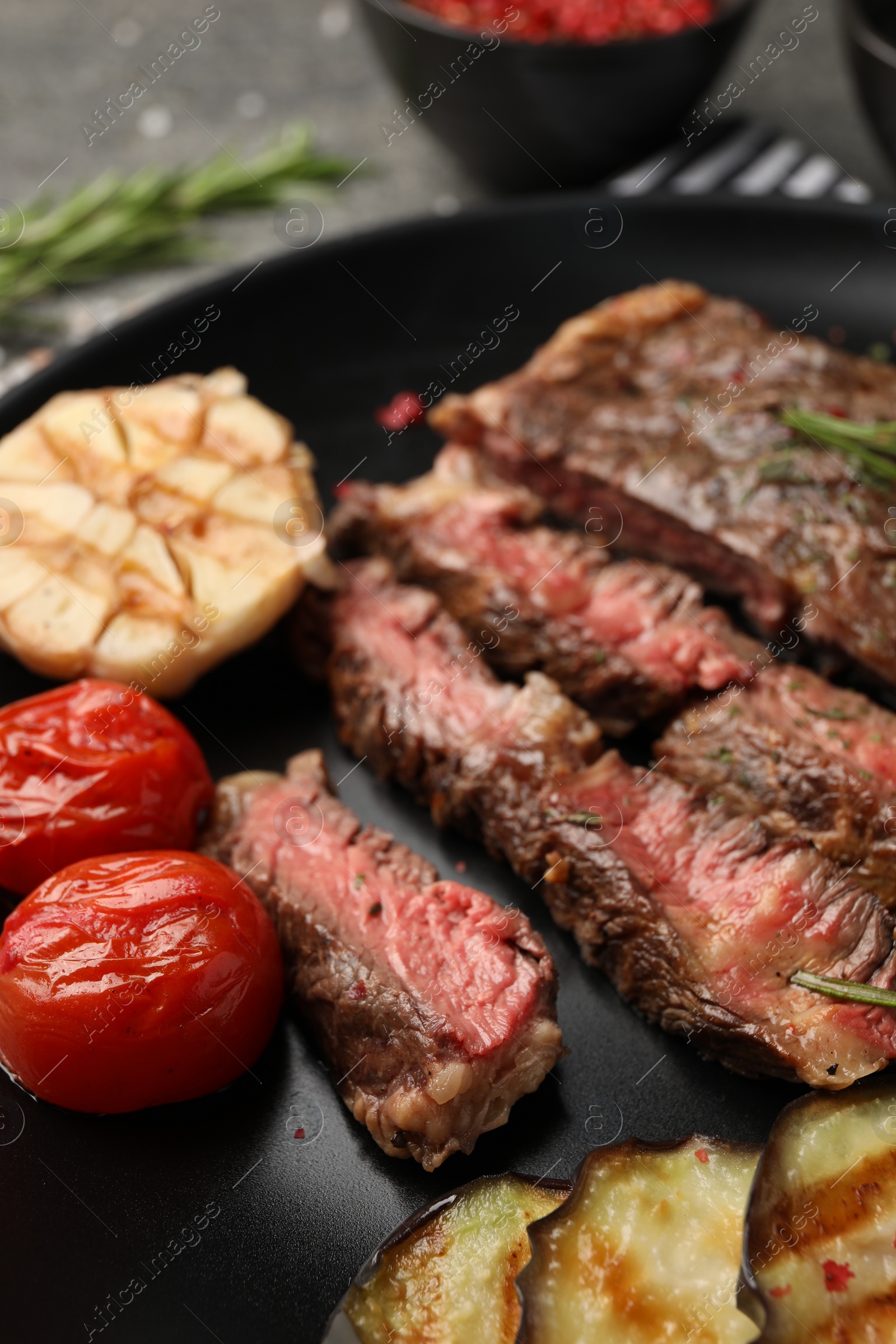 Photo of Delicious grilled beef steak with vegetables and spices on plate, closeup