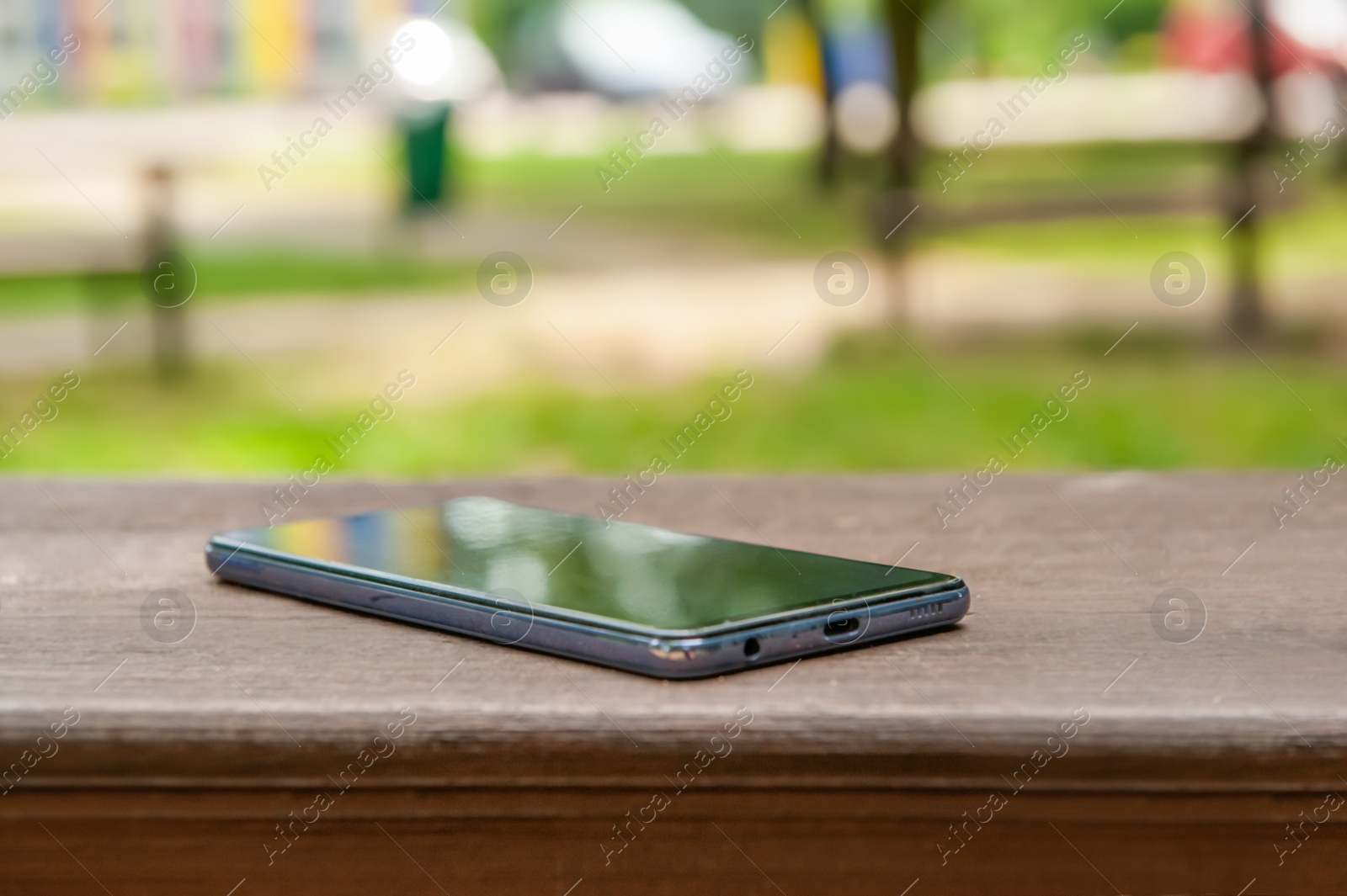 Photo of Smartphone on wooden bench outdoors, space for text. Lost and found