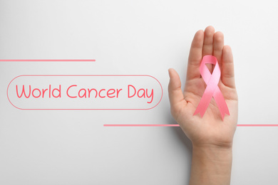 Woman holding pink ribbon on white background, top view. World Cancer Day
