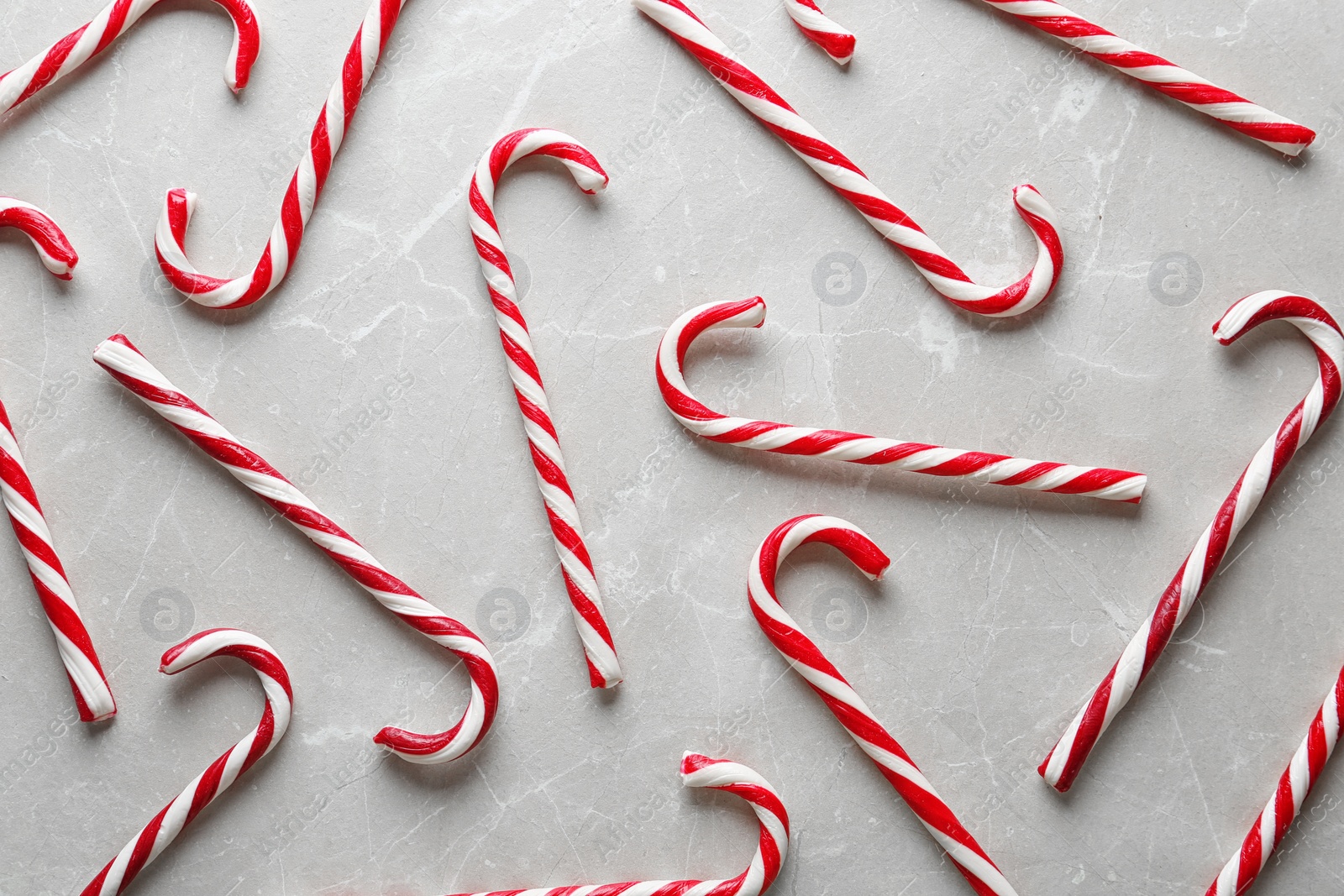 Photo of Flat lay composition with candy canes on grey marble background. Traditional Christmas treat