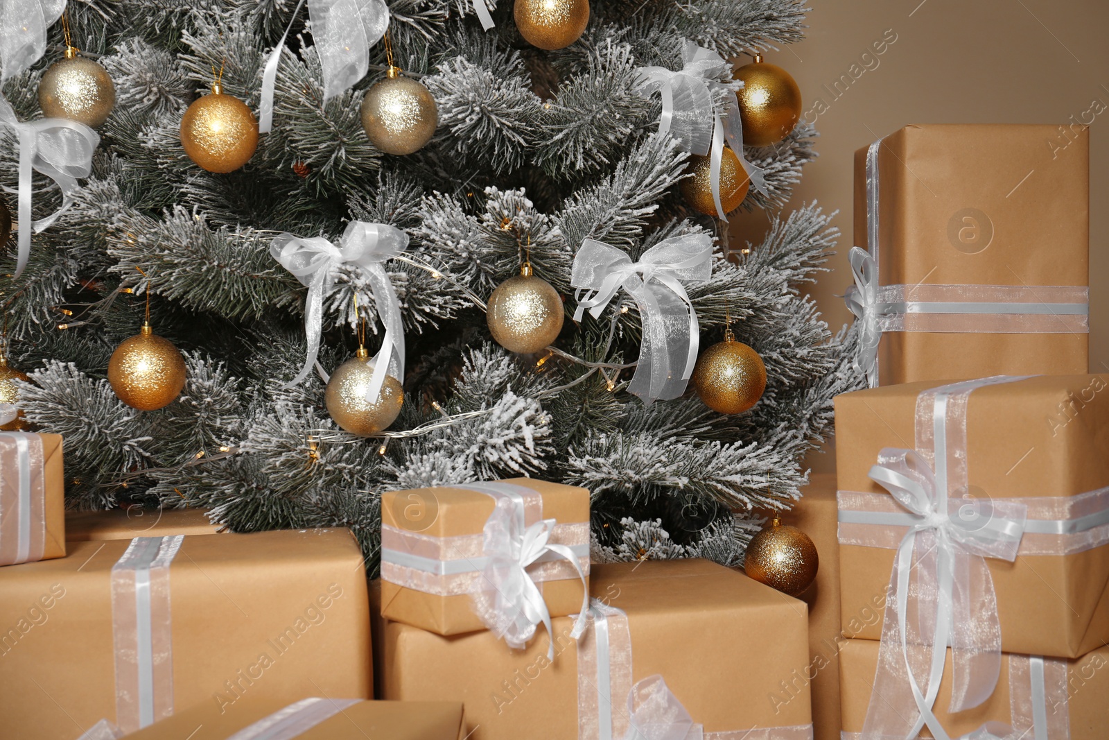 Photo of Decorated Christmas tree with gift boxes against beige background