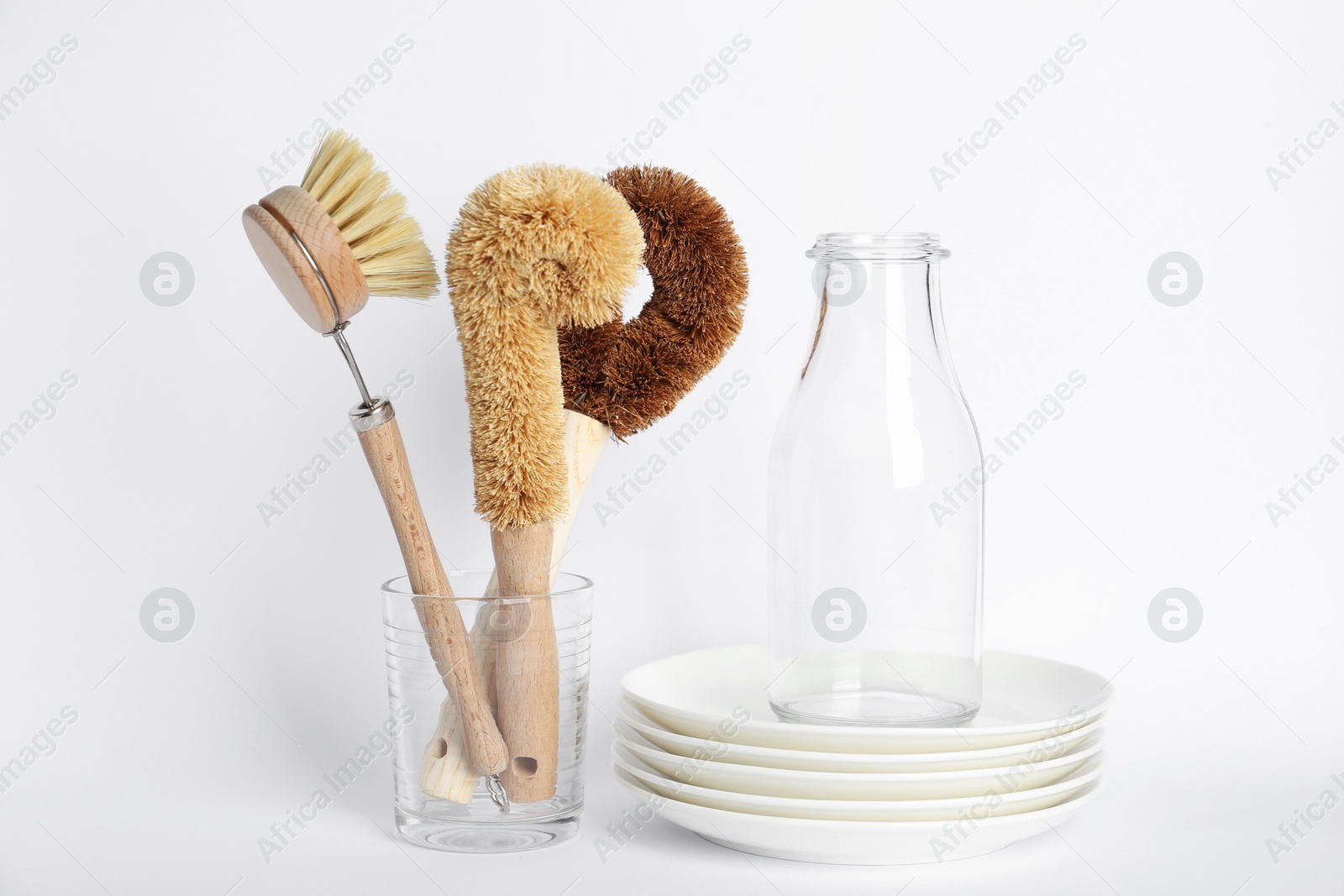 Photo of Cleaning brushes for dish washing, bottle and plates on white background