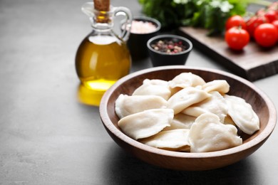 Tasty dumplings in wooden bowl served on grey table. Space for text