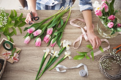 Photo of Female decorator creating beautiful bouquet at table