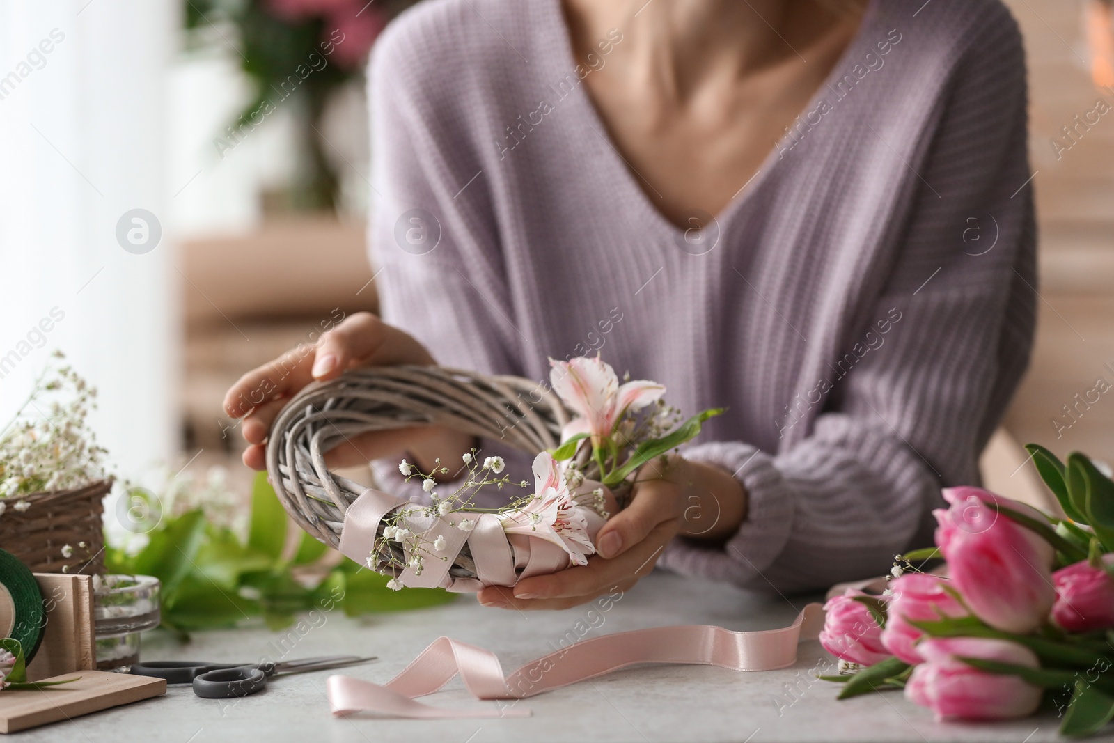 Photo of Female decorator creating beautiful wreath at table