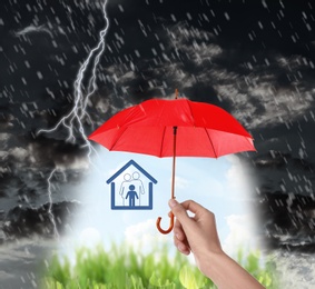 Insurance agent covering illustration with red umbrella during thunderstorm, closeup