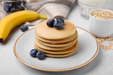 Photo of Tasty oatmeal pancakes on grey table, closeup