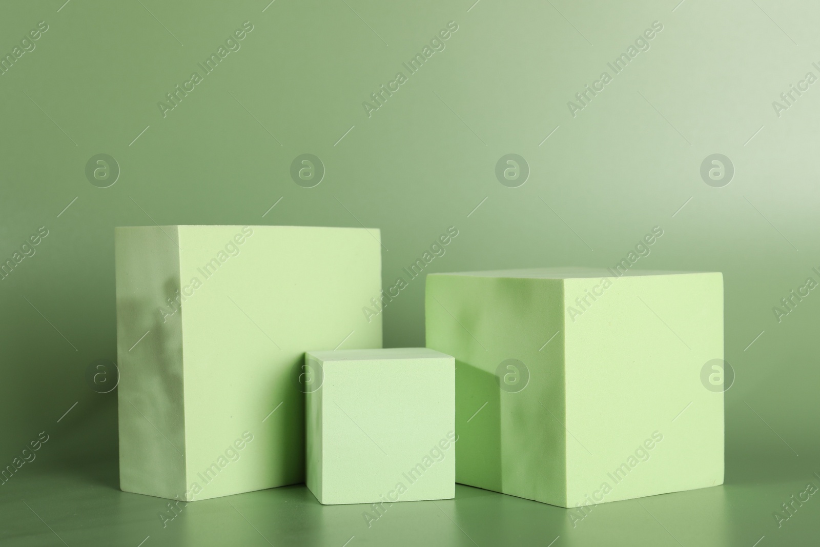 Photo of Presentation of product. Podiums and shadows on green background. Space for text