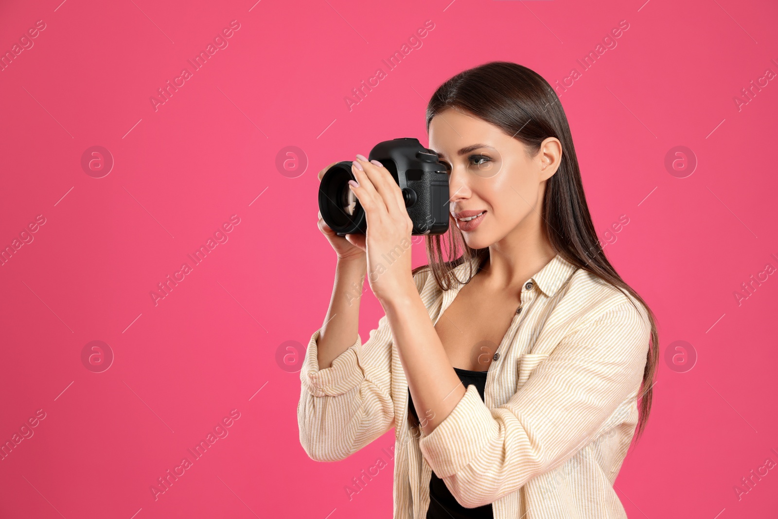 Photo of Professional photographer working on pink background in studio. Space for text