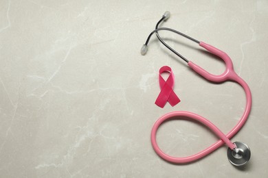Photo of Breast cancer awareness. Pink ribbon and stethoscope on light grey table, flat lay. Space for text