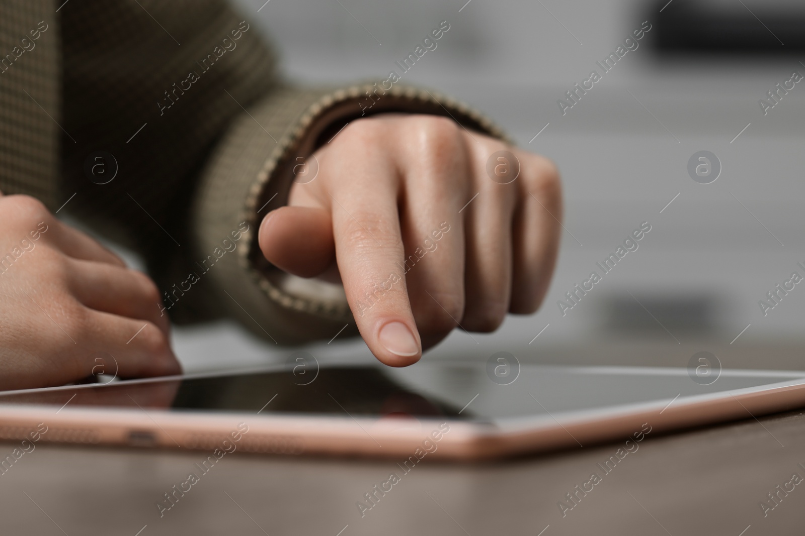 Photo of Closeup view of woman using modern tablet at table on blurred background