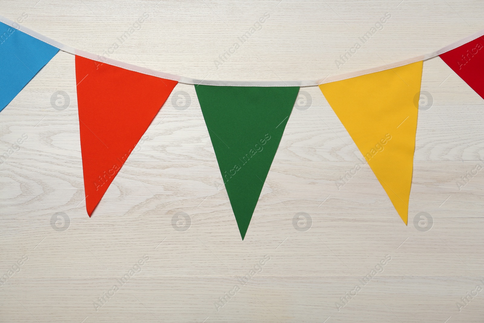 Photo of Bunting with colorful triangular flags on white wooden background