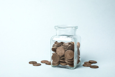 Photo of Glass jar with coins on light background