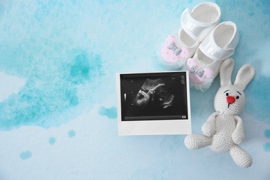 Photo of Ultrasound photo, baby shoes and toy on color background, top view with space for text