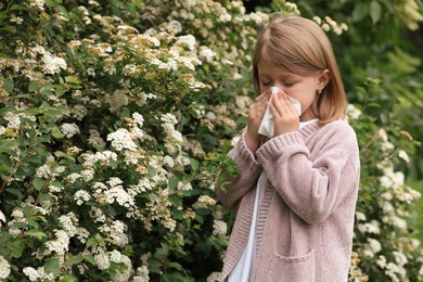 Photo of Little girl suffering from seasonal pollen allergy near blossoming tree on spring day