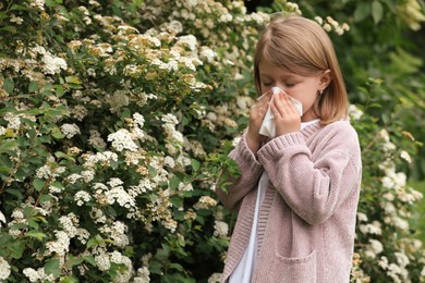 Little girl suffering from seasonal pollen allergy near blossoming tree on spring day