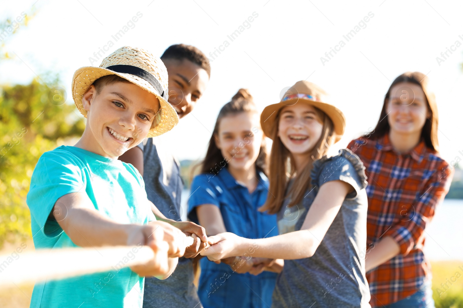 Photo of Group of children pulling rope during tug of war game outdoors. Summer camp