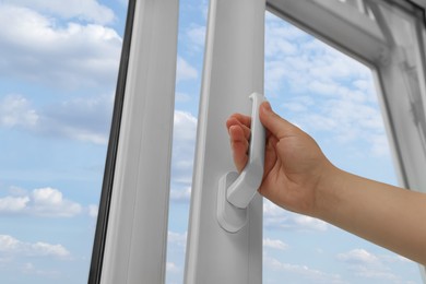 Woman opening white plastic window at home, low angle view