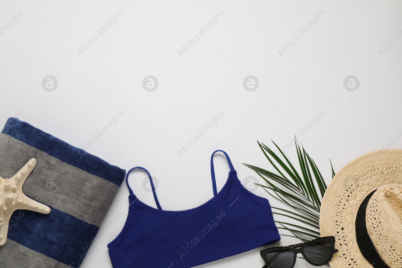 Photo of Beach towel, swimsuit , straw hat and sunglasses on light background, flat lay. Space for text