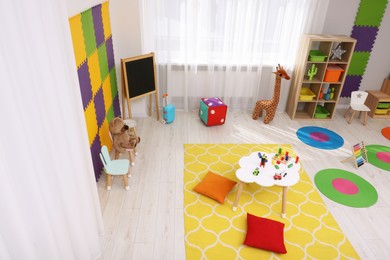 Photo of Child`s playroom with different toys and furniture, above view. Cozy kindergarten interior