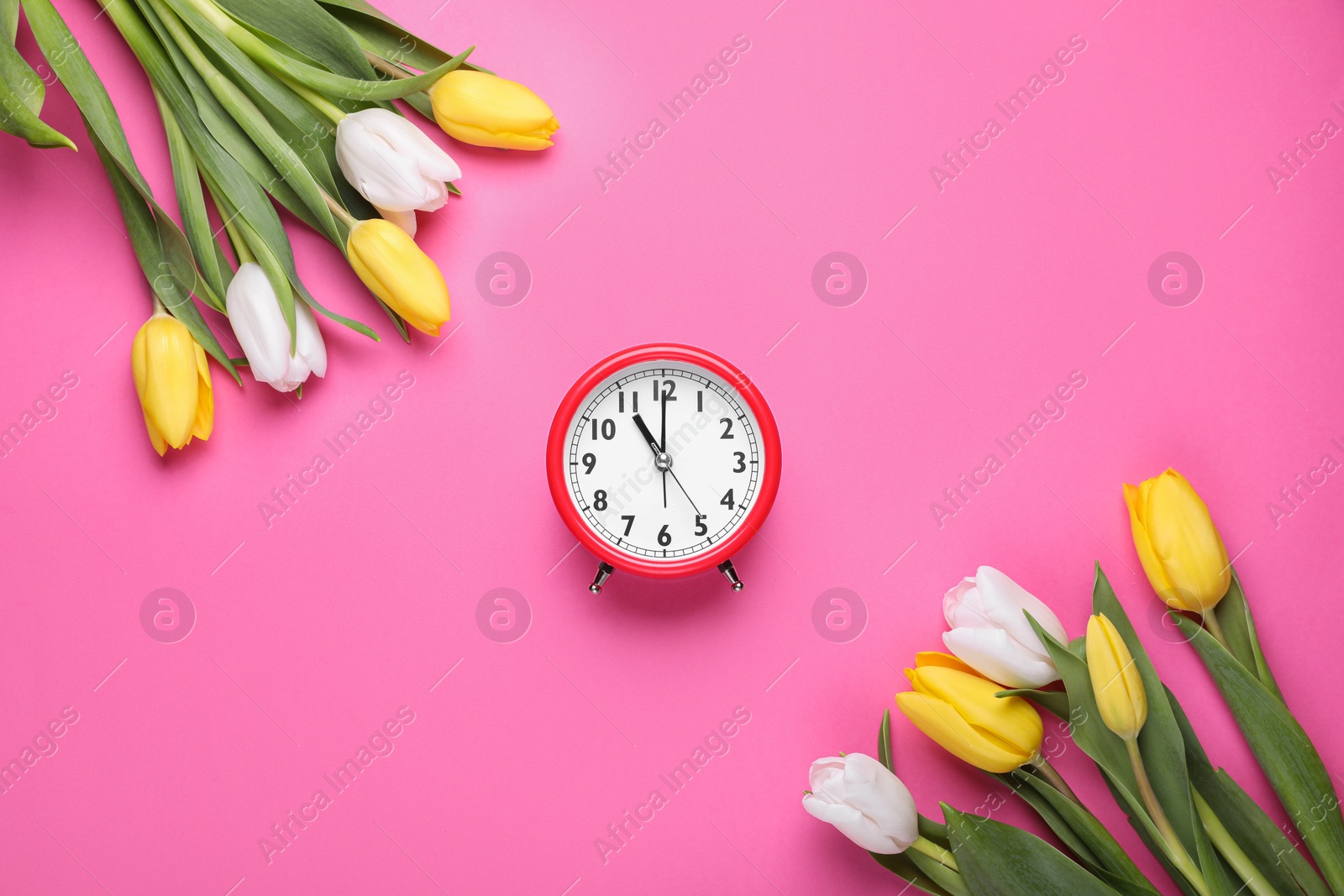 Photo of Red alarm clock and beautiful tulips on pink background, flat lay. Spring time