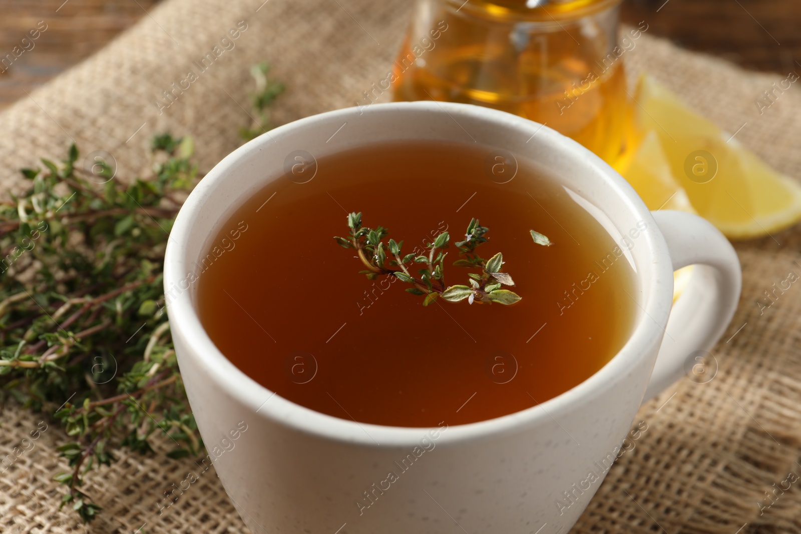 Photo of Aromatic herbal tea with thyme on wooden table, closeup