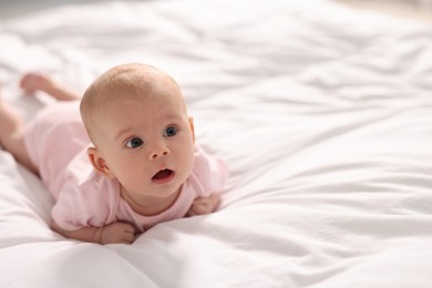 Photo of Cute little baby lying on white sheets, space for text