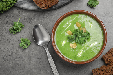 Tasty kale soup served on grey table, flat lay