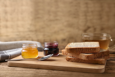 Photo of Delicious crispy toasts and jams on wooden table