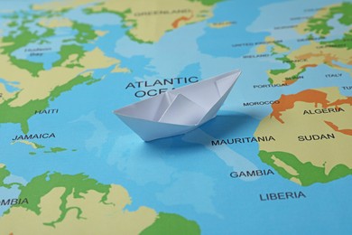 Photo of One white paper boat on world map
