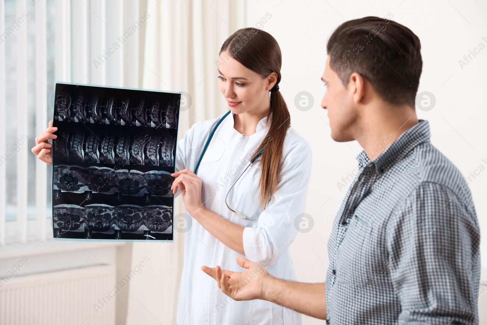 Photo of Orthopedist showing X-ray picture to patient in clinic