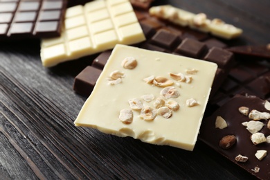 Different chocolate bars with nuts on wooden background