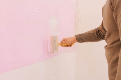 Decorator painting wall with brush indoors, closeup