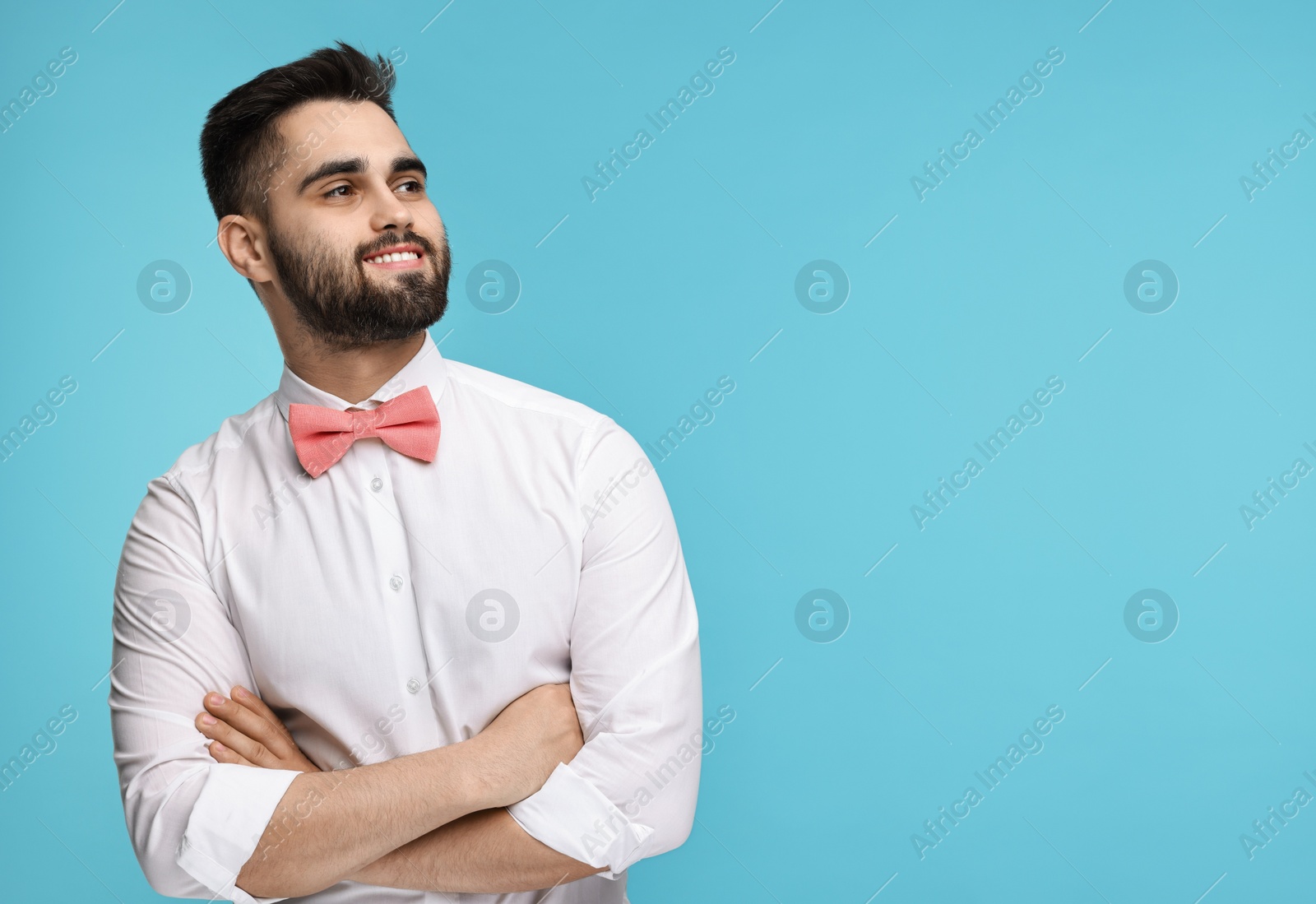 Photo of Portrait of smiling man in shirt and bow tie on light blue background. Space for text