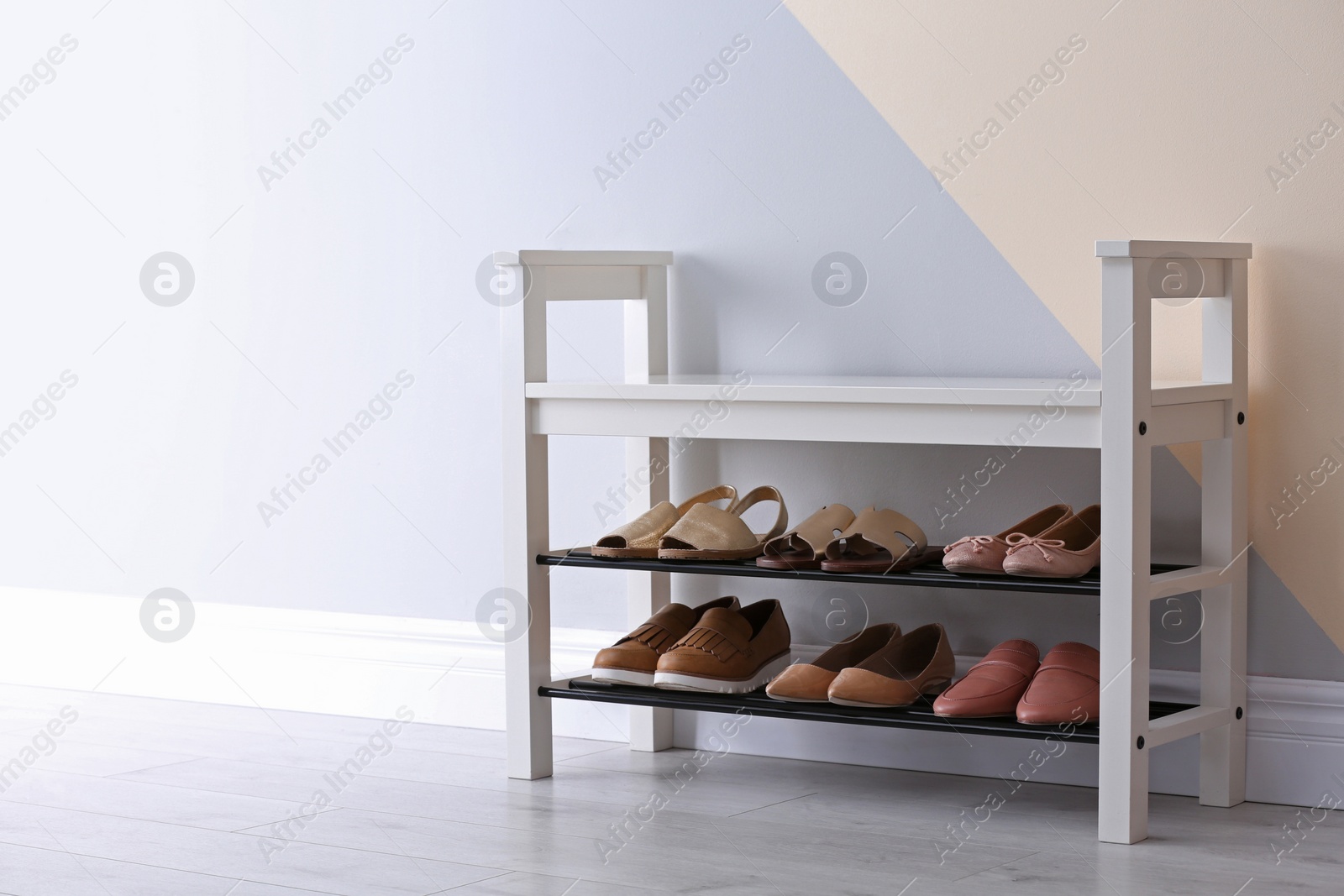 Photo of Shoe rack with different footwear near color wall, space for text. Stylish hallway interior