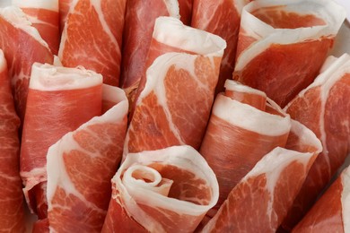 Rolled slices of delicious jamon as background, closeup