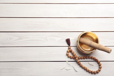 Photo of Flat lay composition with golden singing bowl on white wooden table, space for text. Sound healing