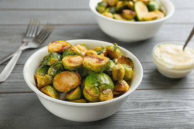 Photo of Delicious roasted brussels sprouts served on grey wooden table, closeup