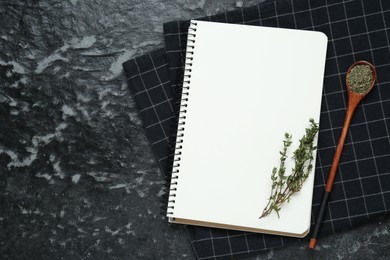 Photo of Blank recipe book and thyme on black textured table, flat lay. Space for text