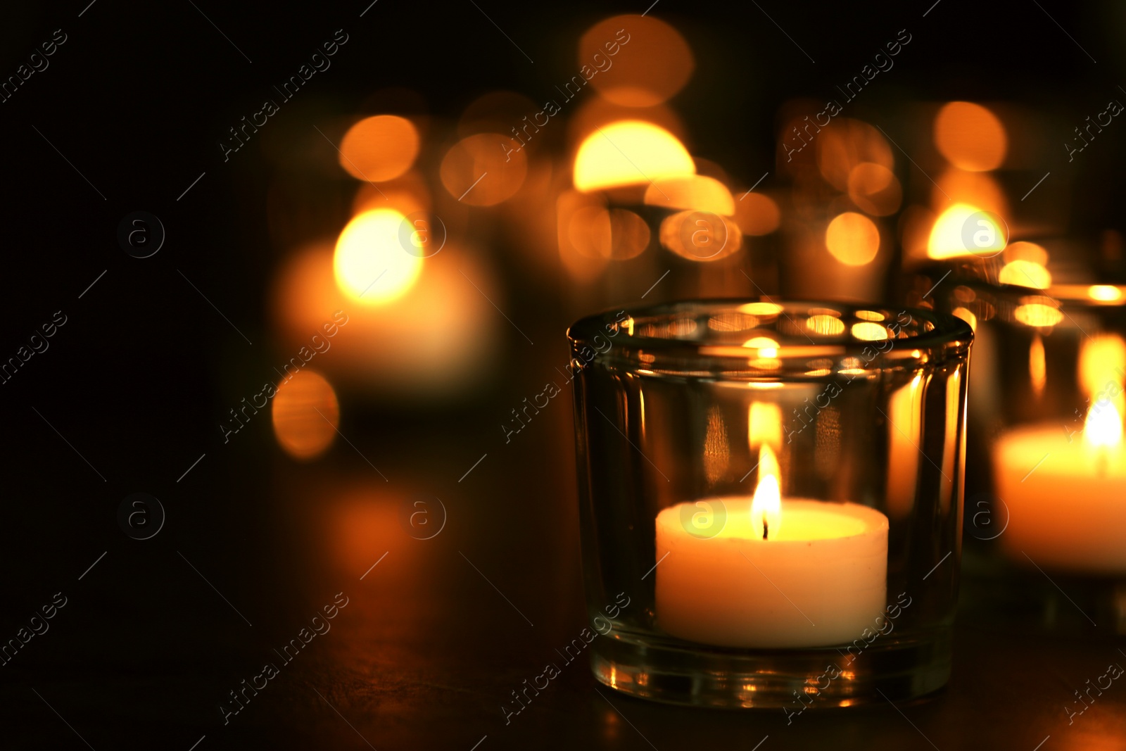 Photo of Burning candle on table against blurred background, space for text. Funeral symbol