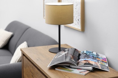 Open sports magazine and lamp on cabinet in living room