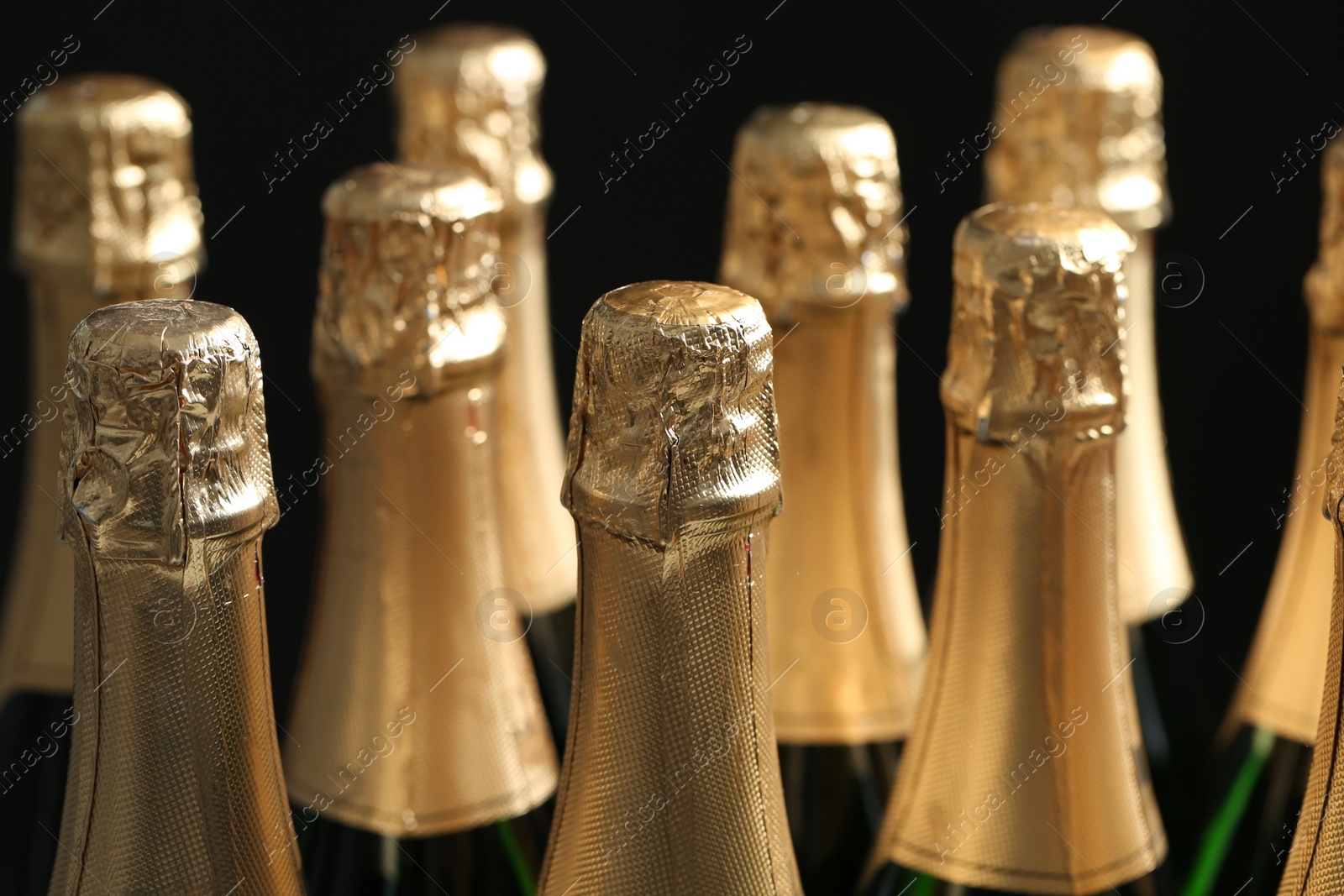 Photo of Many bottles of champagne on dark background, closeup