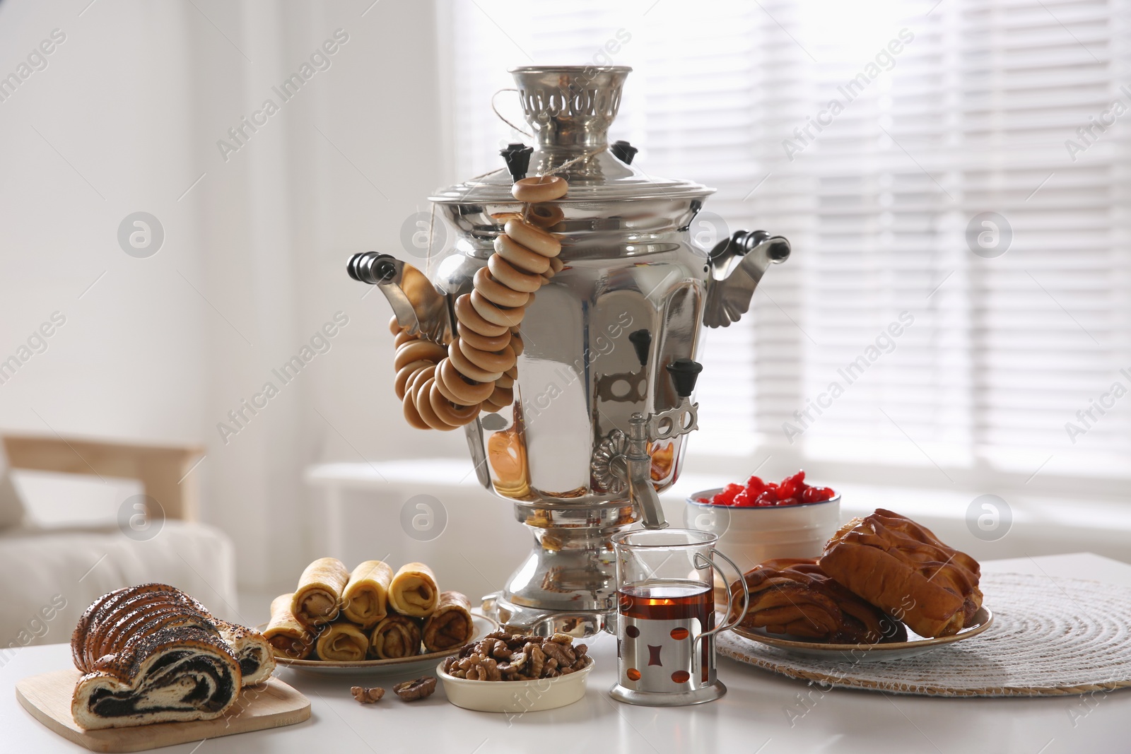 Photo of Traditional Russian samovar with treats on white table at home