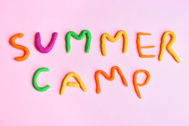 Photo of Words SUMMER CAMP made from modelling clay on color background, top view