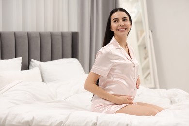 Photo of Happy pregnant woman on bed at home, space for text